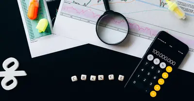 Desk with printed charts, a calculator and a magnifier set up for forecasting