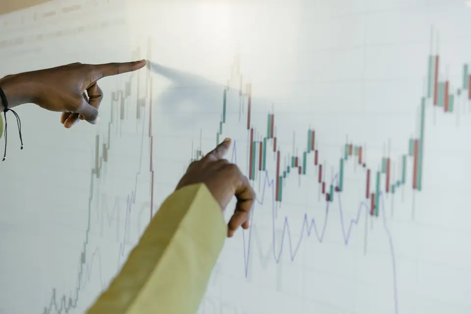 Analyst pointing at a volatile chart while reviewing forecast confidence