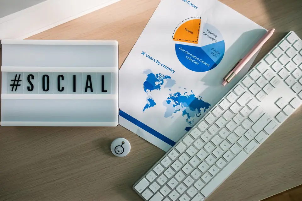 Illuminated '#social' sign beside printed campaign reports and charts