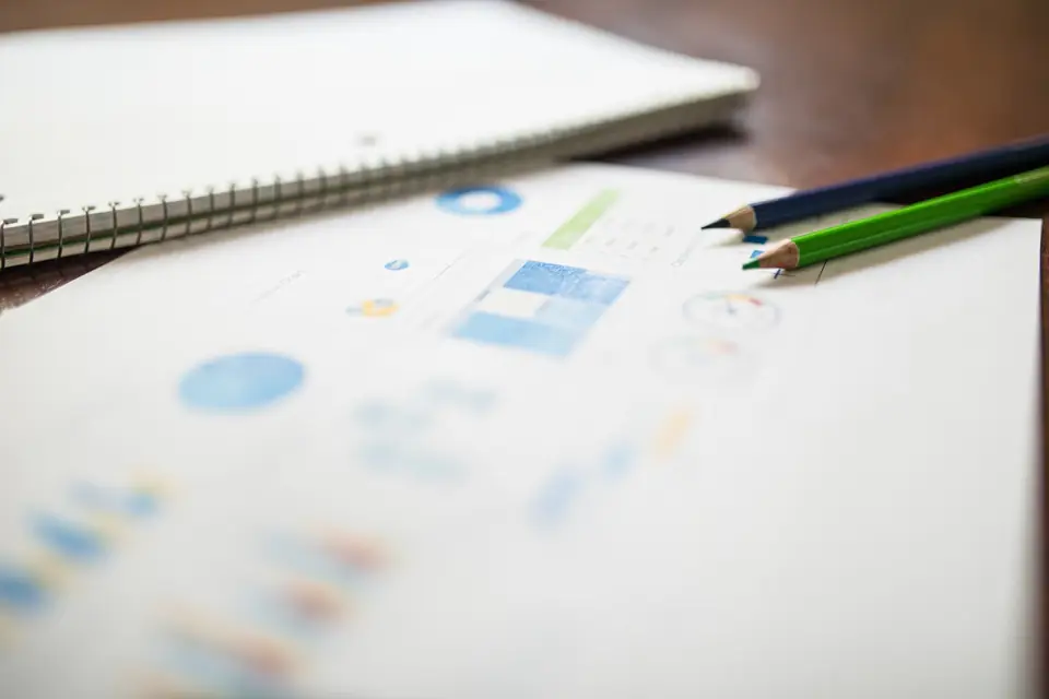 Notebook and coloured pencils laid out beside printed charts