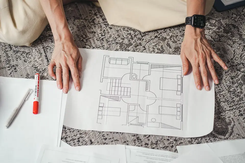 Hands laying out a floor plan, designing the structure before building it