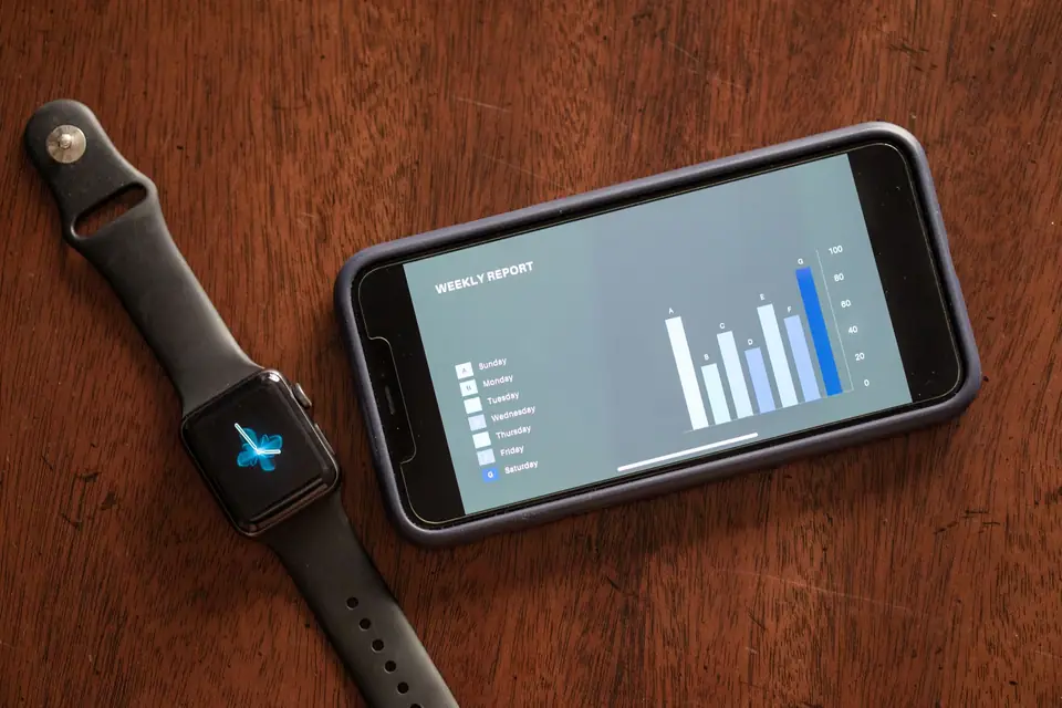 Weekly report chart on a phone beside a smartwatch